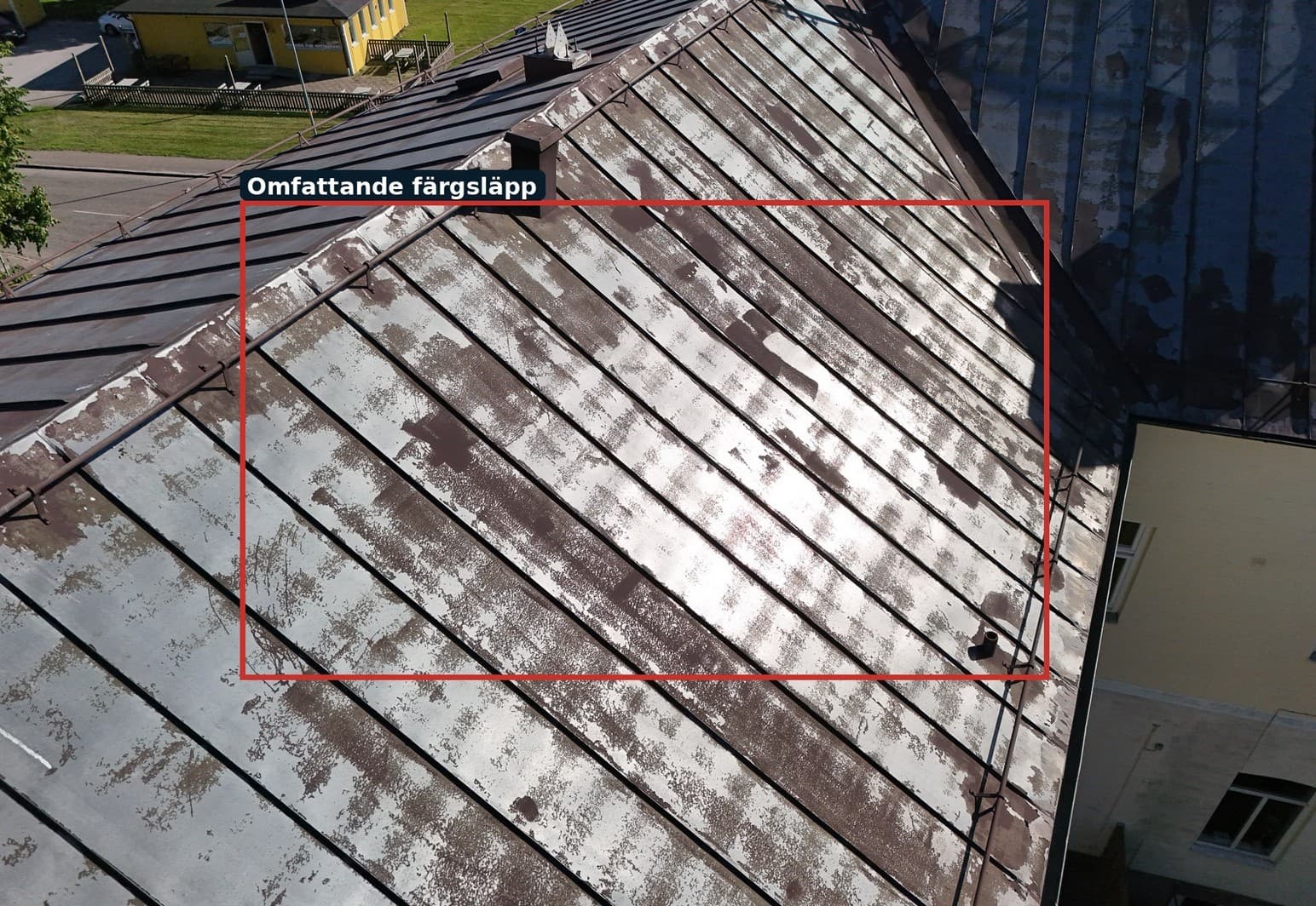 Detaljbild av nedbrutet färgskikt på plåttaket